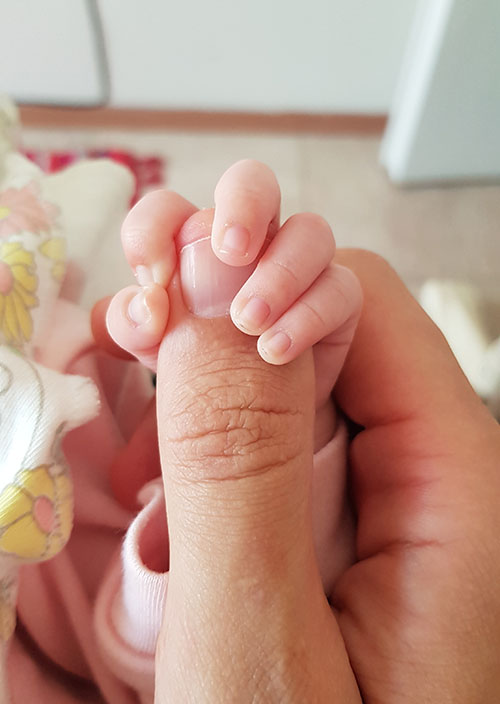 Nyfött barns fingrar lindade runt pappans finger
